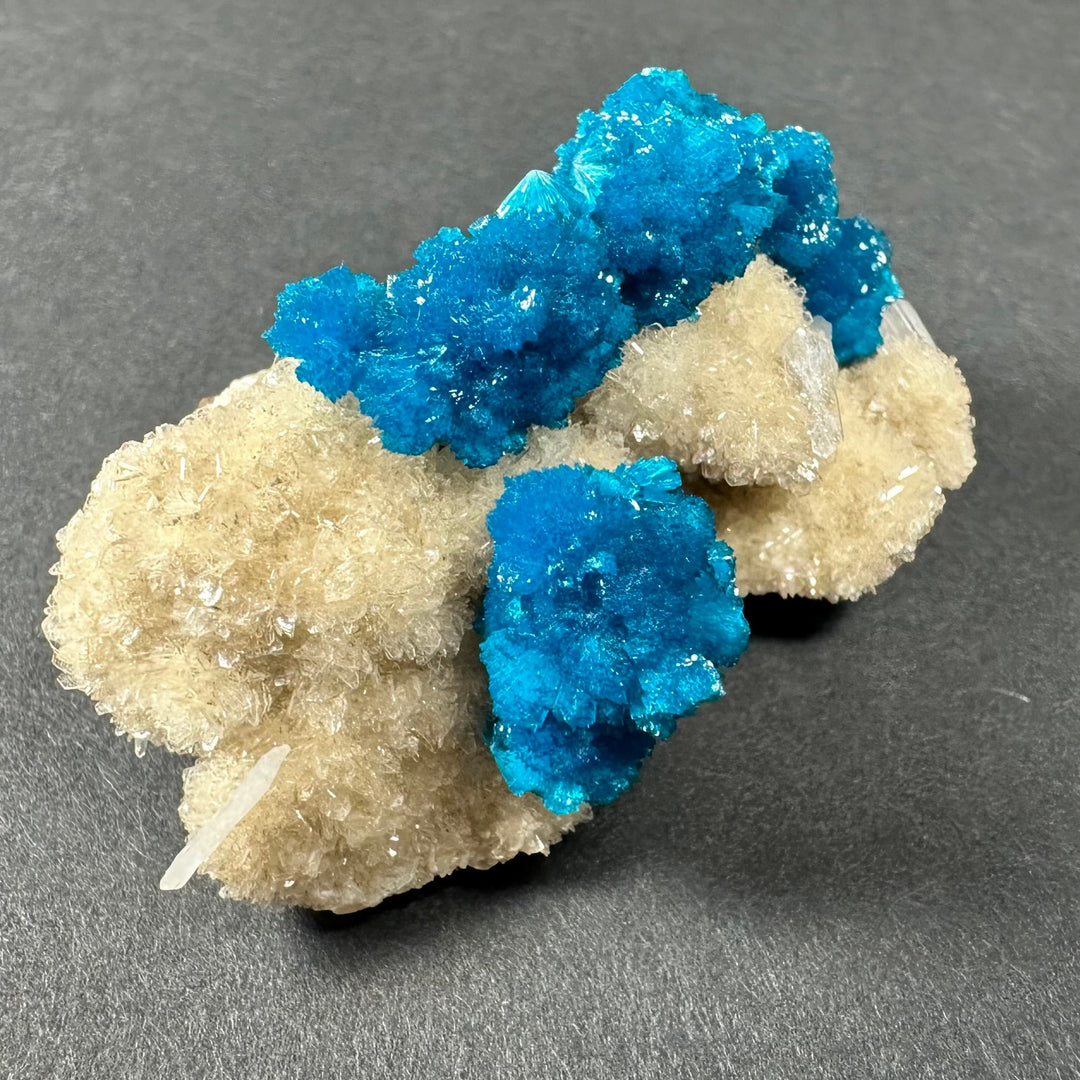 Cavansite and stilbite crystal cluster on beige matrix with bright blue central chunk