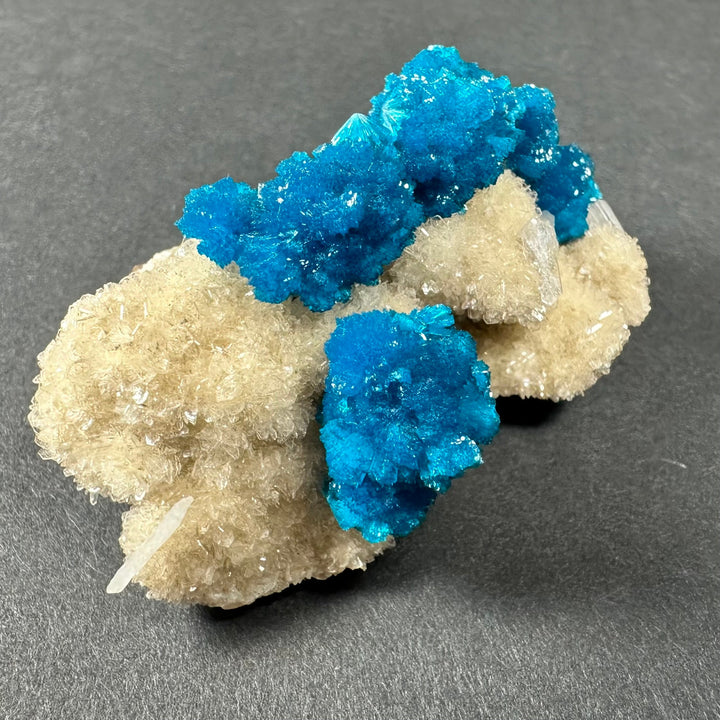 Cavansite and stilbite crystal cluster on beige matrix with bright blue central chunk