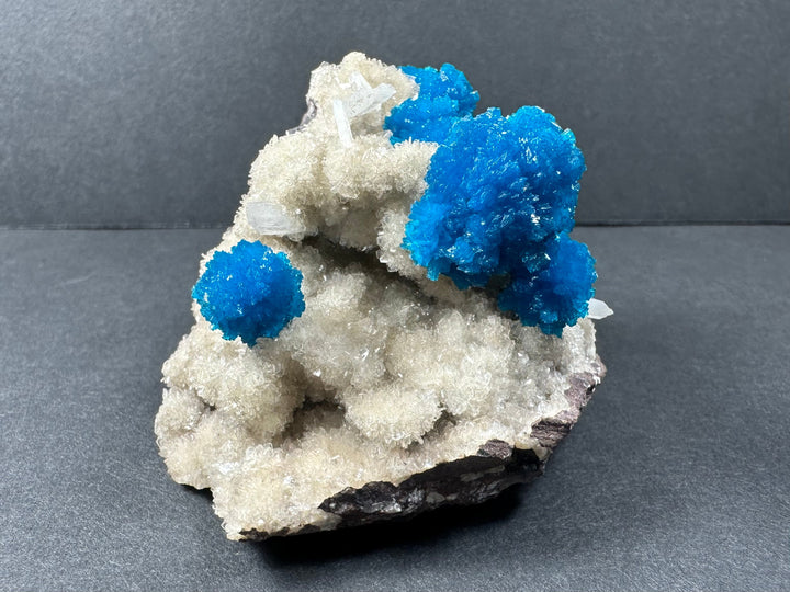 Cavansite and stilbite specimen with one main vivid blue cluster on pale white matrix