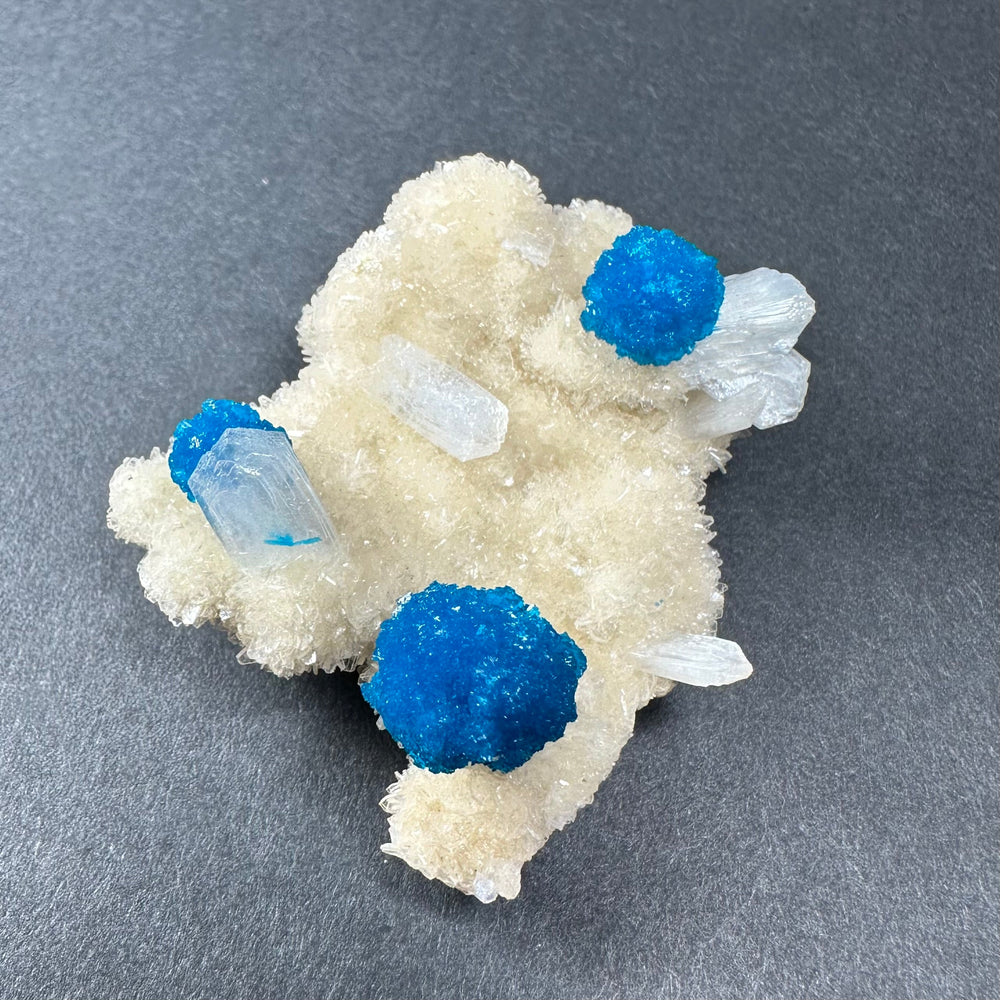 Stilbite matrix with pale beige druzy surface, blue cavansite spheres, clear blades