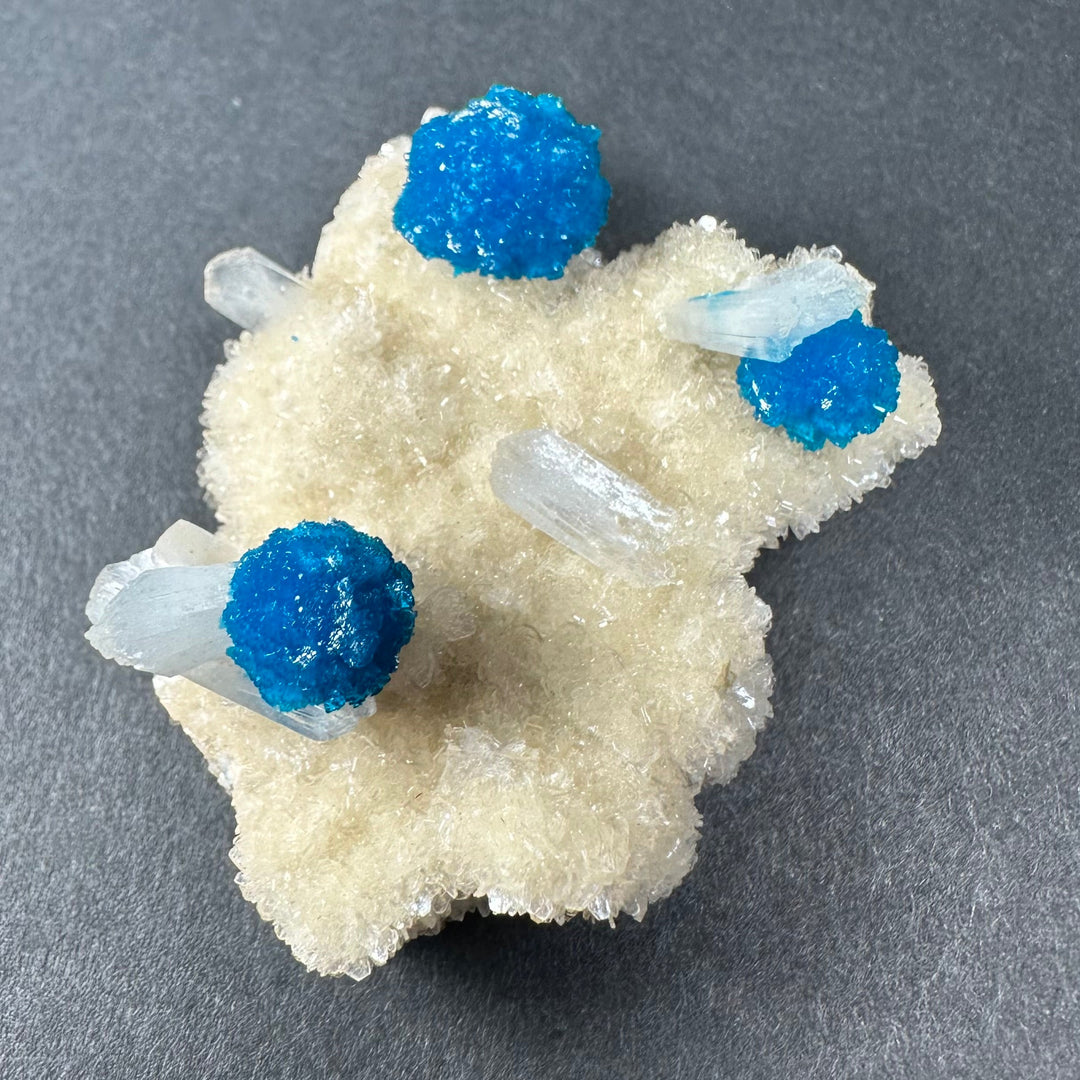 Beige stilbite matrix with vivid blue druzy nodules and several clear crystalline pieces