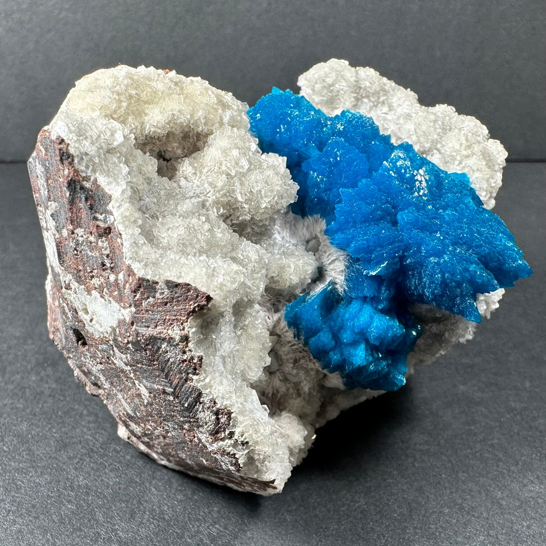 Blue and white mineral crystal cluster on brown-gray rock matrix