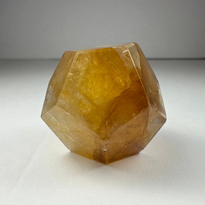 Yellow hematoid quartz dodecahedron carving with honey-gold translucence and crisp edges