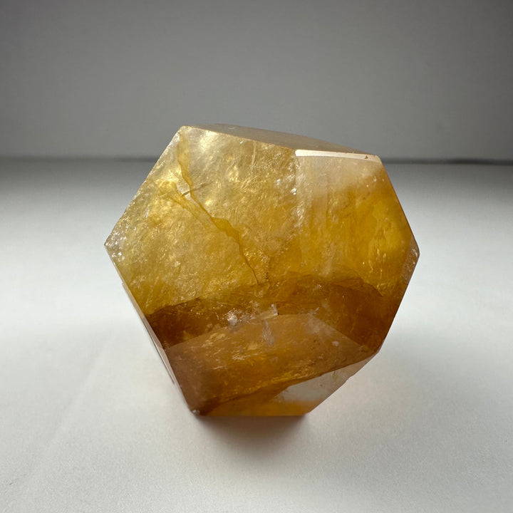 Yellow hematoid quartz dodecahedron with rich amber color and faceted geometry