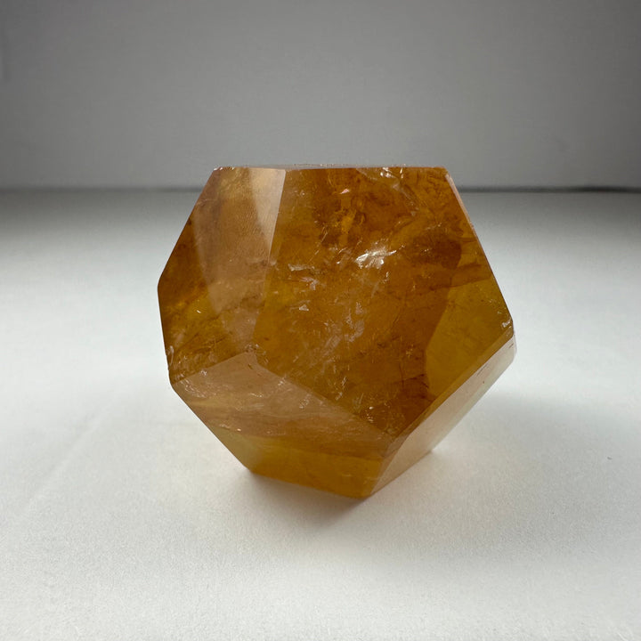 Yellow hematoid quartz dodecahedron with smooth facets and translucent warm-gold tone