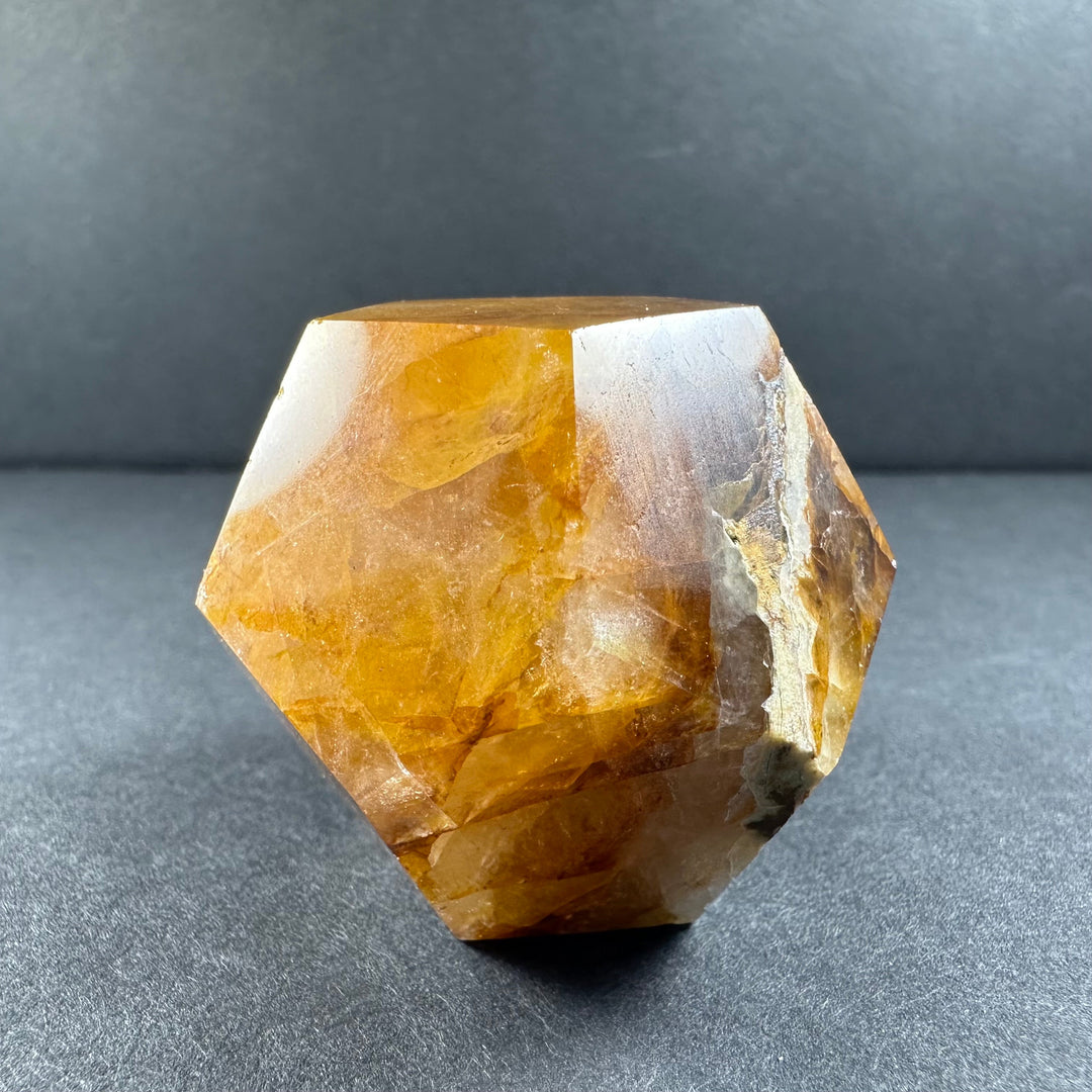 Yellow hematoid quartz dodecahedron with faceted surface and light gray stone patches