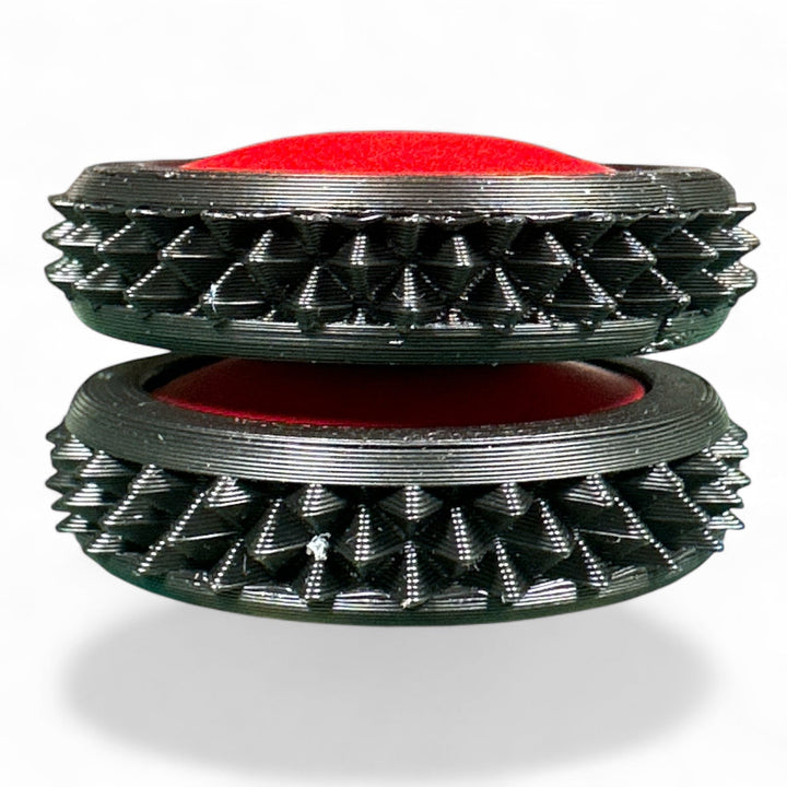 Black and red spiky fidget gear discs stacked, showing oval center opening