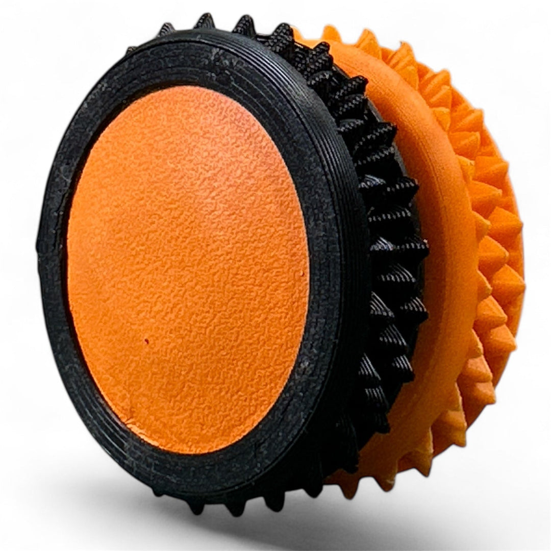 Black and orange fidget gear with textured rings and oval center pad
