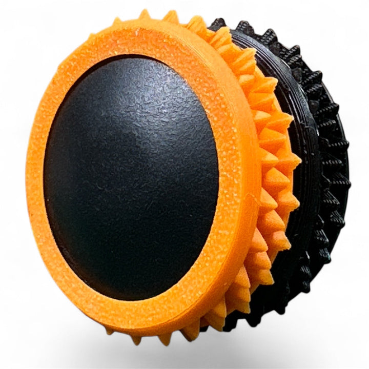 Orange and black fidget gear with spiky ring detail and oval center pad