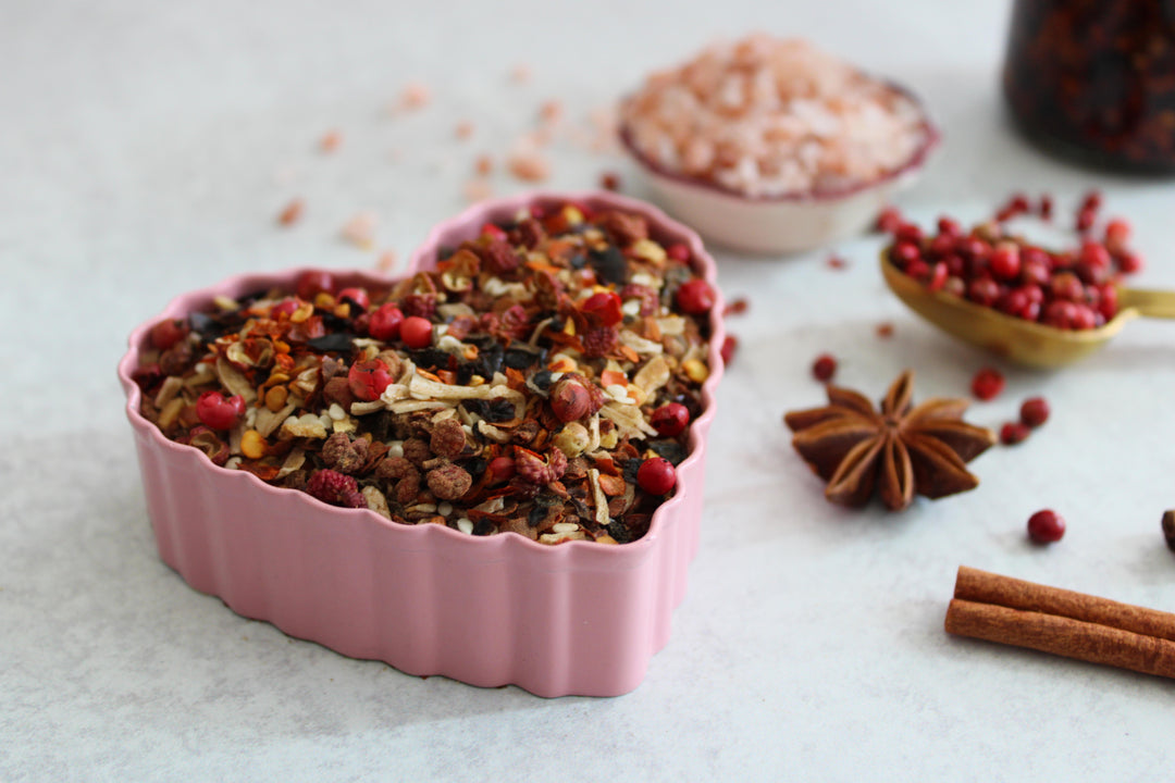 Chili crisp in a pink ramekin dish with scattered spices and peppers