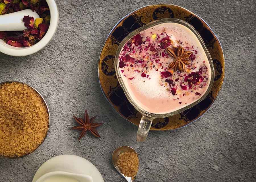 Pink chai latte in glass cup with pink foam and star anise spice