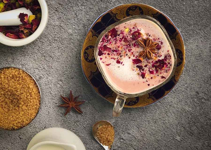 Pink chai latte in glass cup with pink foam and star anise spice
