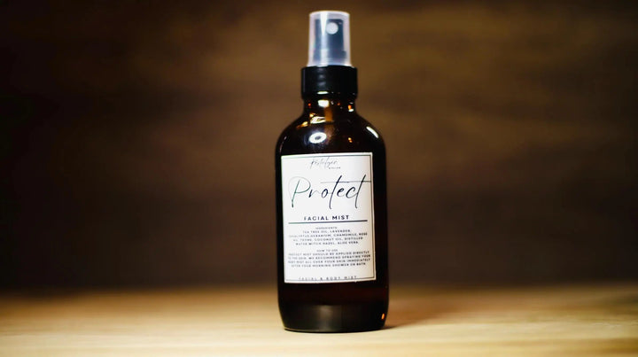 Facial mist spray bottle with silver pump, dark amber liquid, "Protect" label