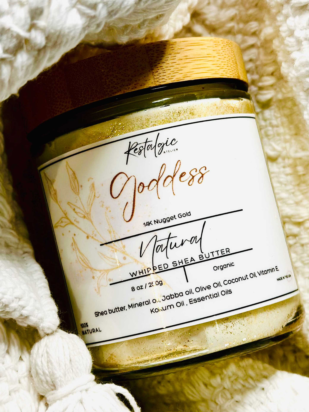 Shimmer body butter jar close-up on white knit background, gold cap and label visible