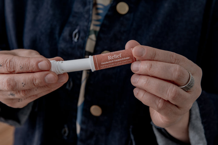 Aromatherapy inhaler tube with Relief label, held in hands.