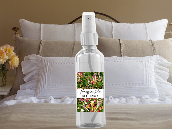 Room spray bottle with white pump on layered white ruffles and neutral pillows