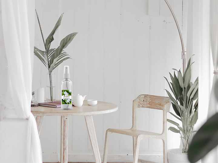 Room and linen spray bottle with floral label on round wooden side table