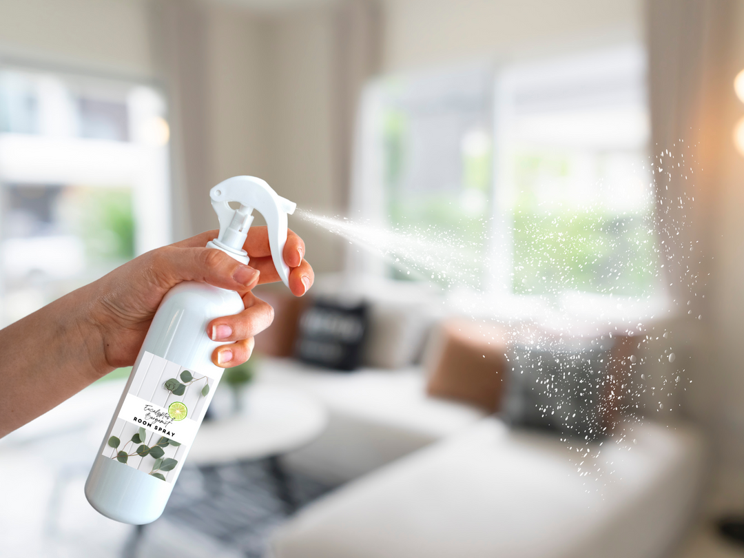 White room spray bottle with trigger nozzle, held in hand releasing mist