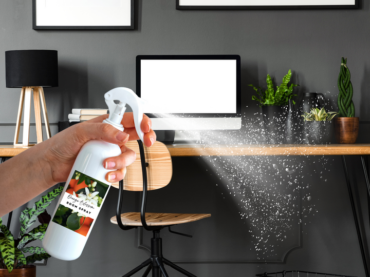White room spray bottle with trigger nozzle spraying mist near an indoor plant
