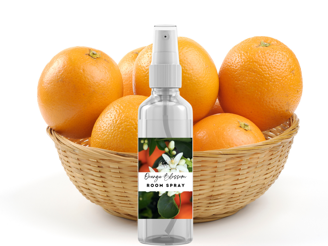 Room spray bottle with white pump centered in a wicker basket of oranges