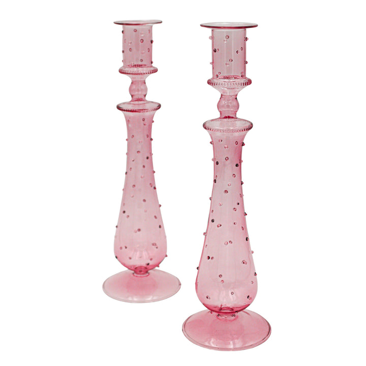 Pair of pink dotted glass candle holders with fluted stem and round base.
