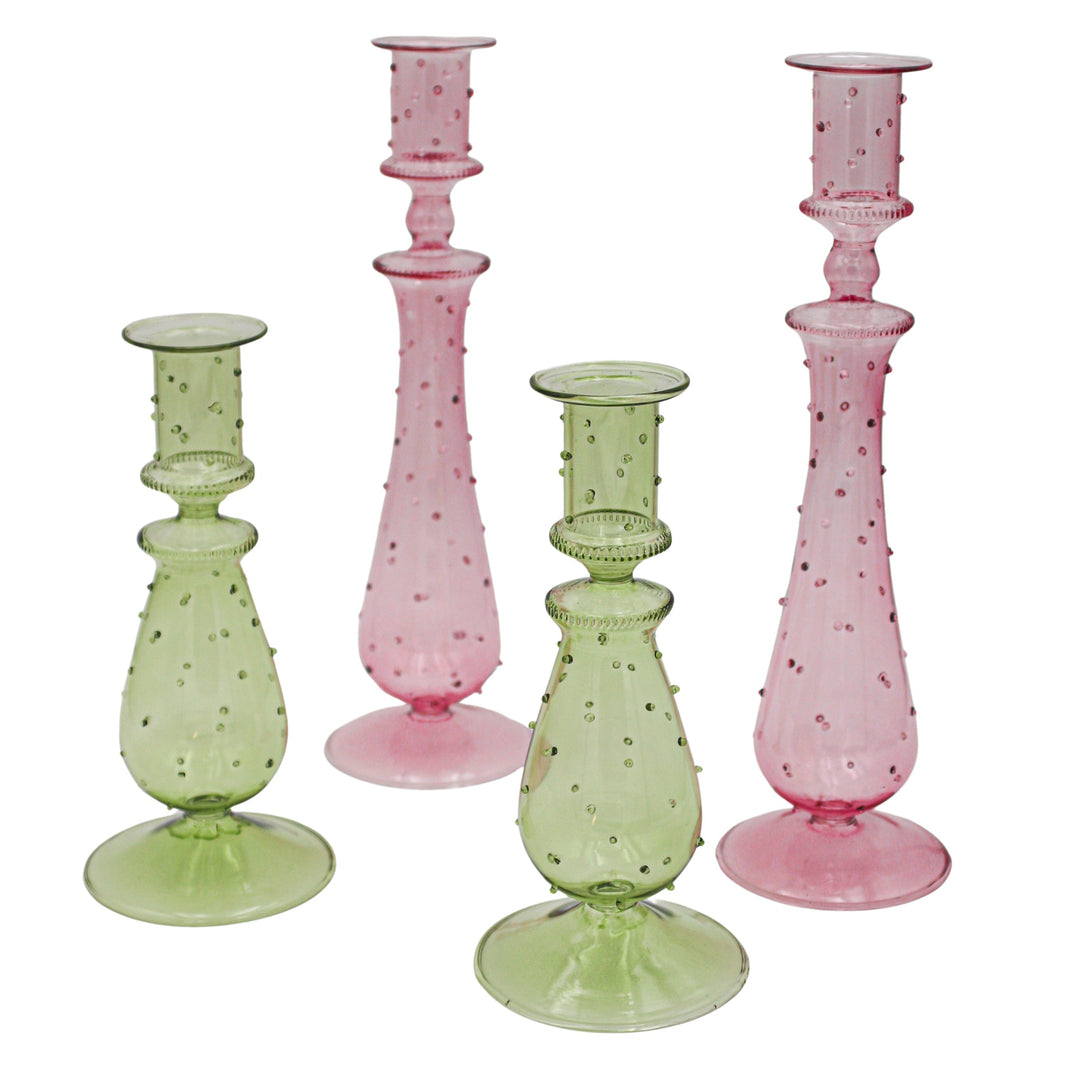 Pair of tall dotted glass candle holders in pink and green with wide round bases.