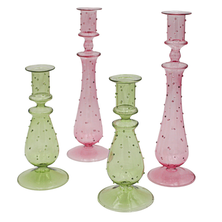 Pair of tall dotted glass candle holders in pink and green with wide round bases.