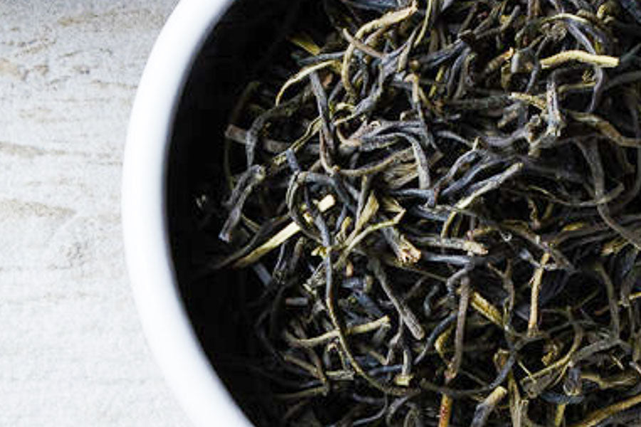 Loose leaf green tea leaves in a white bowl
