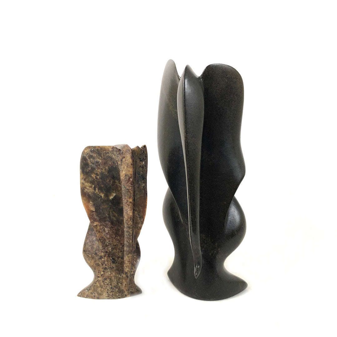Stone elephant figurines, one dark gray-black and one speckled brown, carved upright