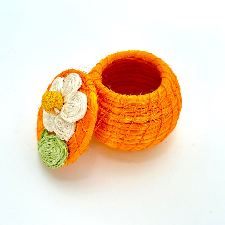 Orange round woven tiny basket with white, yellow, and green flowers; open bowl interior visible.