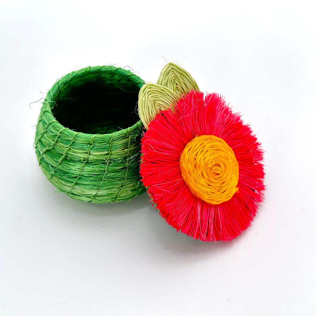 Tiny woven basket with open top, green body, and red flower lid with yellow center.