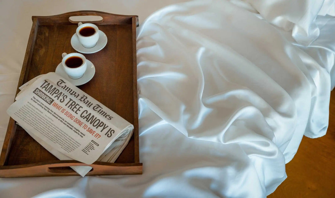 Lightly wrinkled white sheet fabric beside a wooden tray and cups