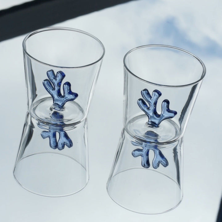 Water tumbler pair with clear glass and dark blue coral-shaped silicone inserts