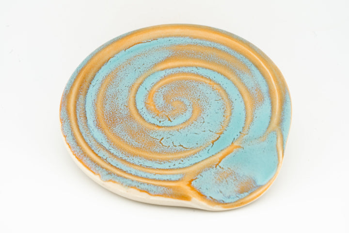Blue and yellow ceramic spoon rest with concentric swirl glaze and curved rim