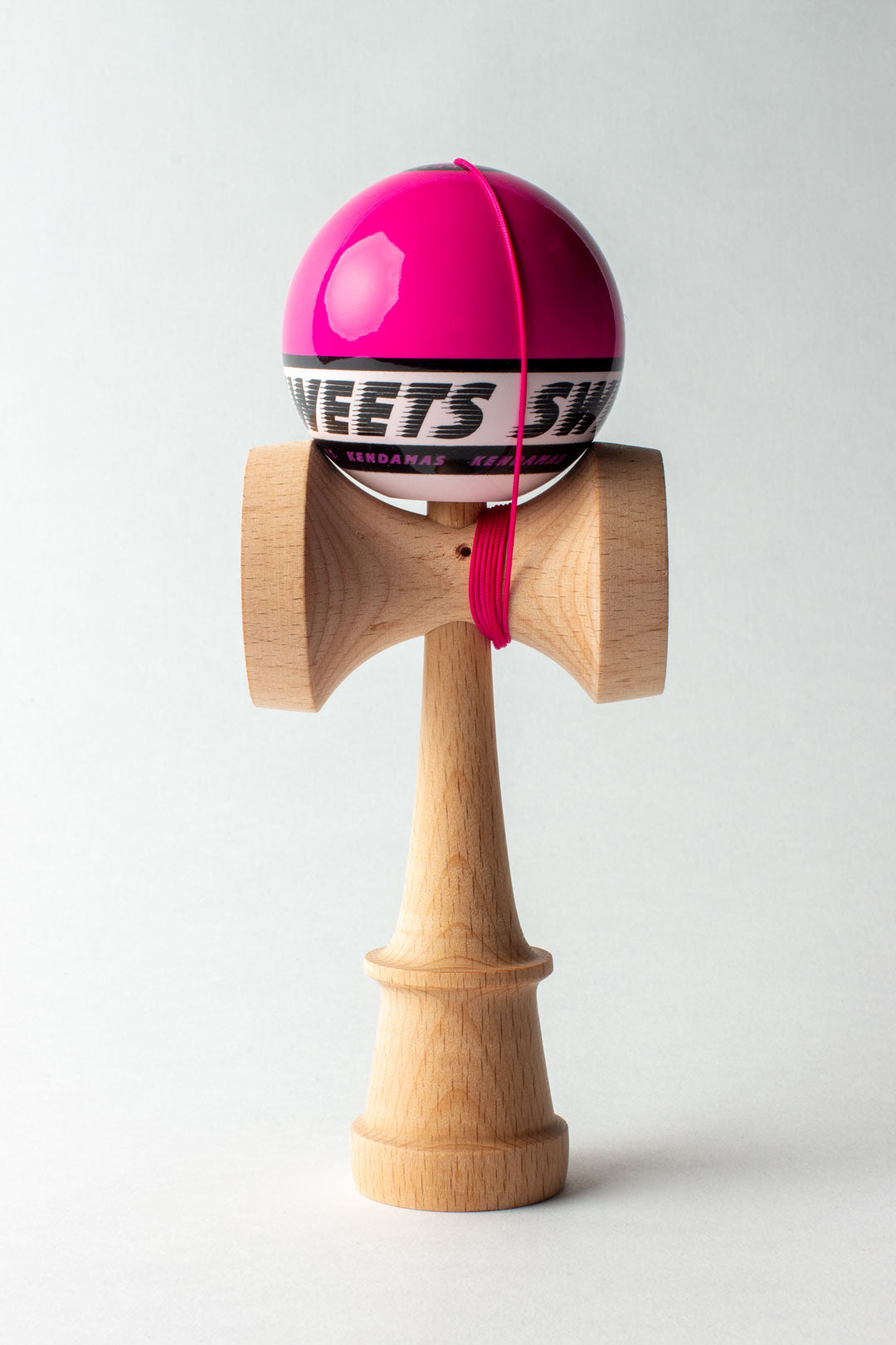 Wooden kendama with pink ball and red string, front view