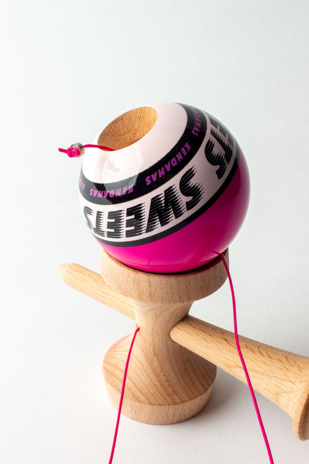 Wooden kendama with pink ball and logo band, close-up on wooden handle