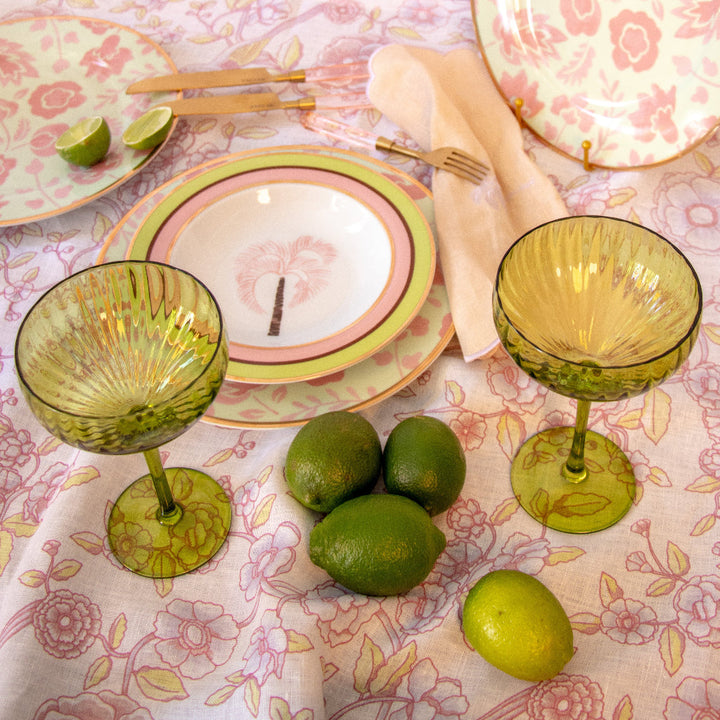 Ribbed sage-green coupe glass held on table with another matching glass visible.