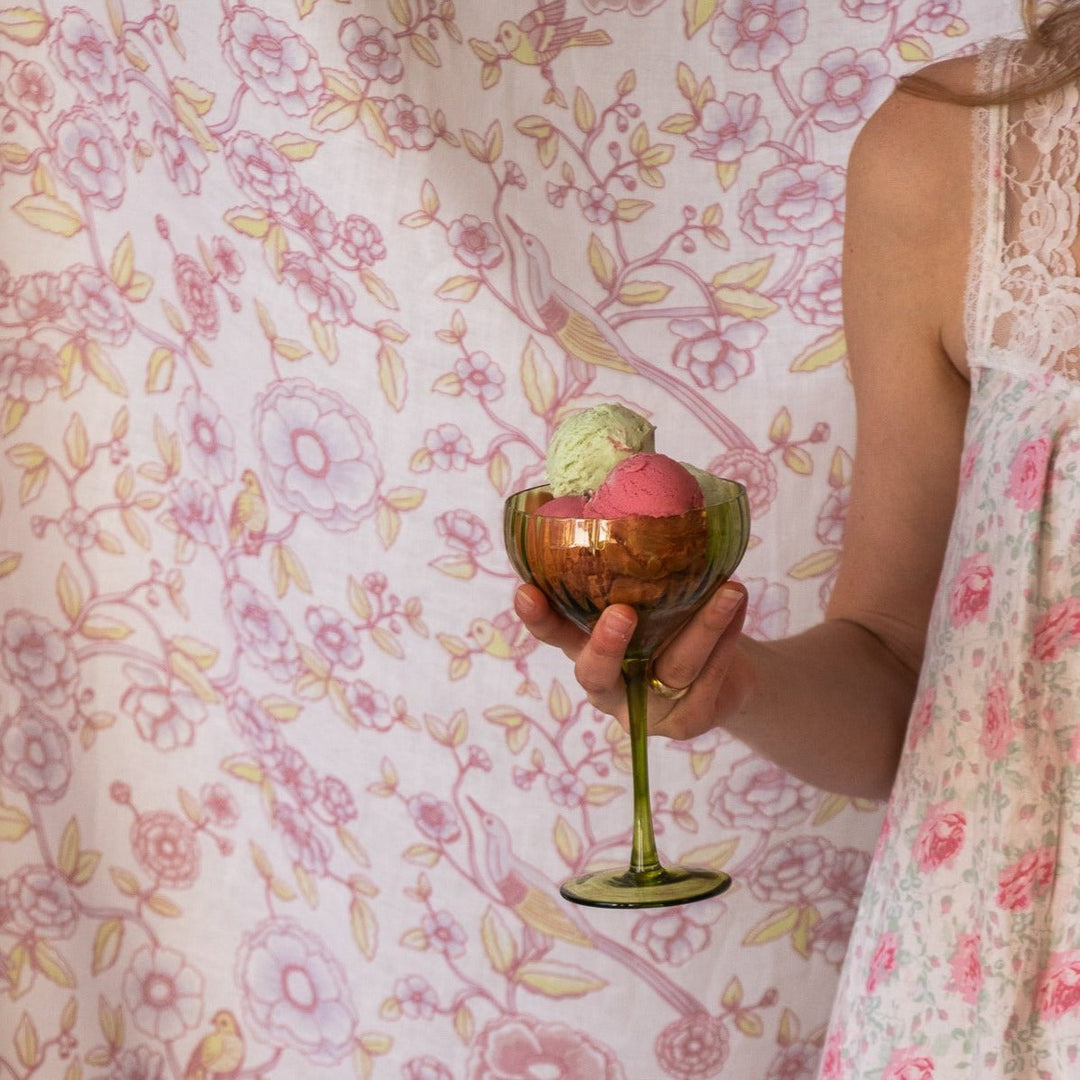 Ribbed sage-green coupe glass with dessert, held by person wearing a floral dress.