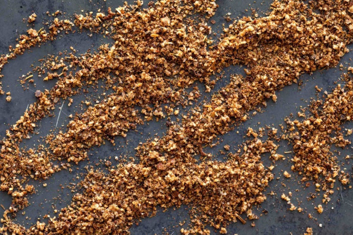 Golden spice rub granules sprinkled on a blue-gray surface