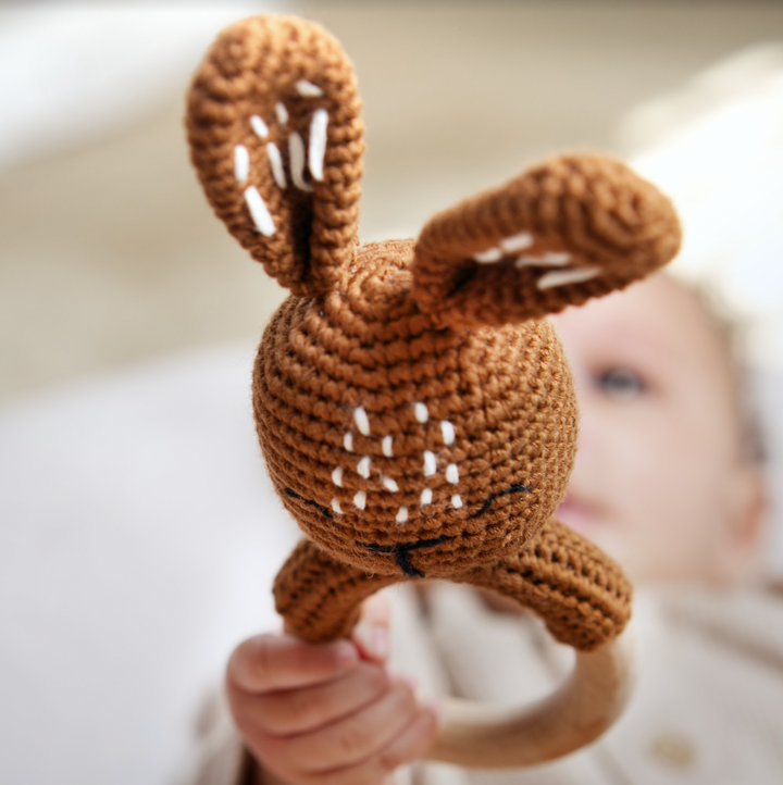 Brown bunny crochet rattle teether with wooden ring, held in a baby's hands