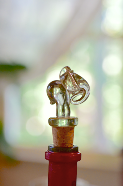 Animal-shaped glass wine stopper with brown cork and amber figure on red base