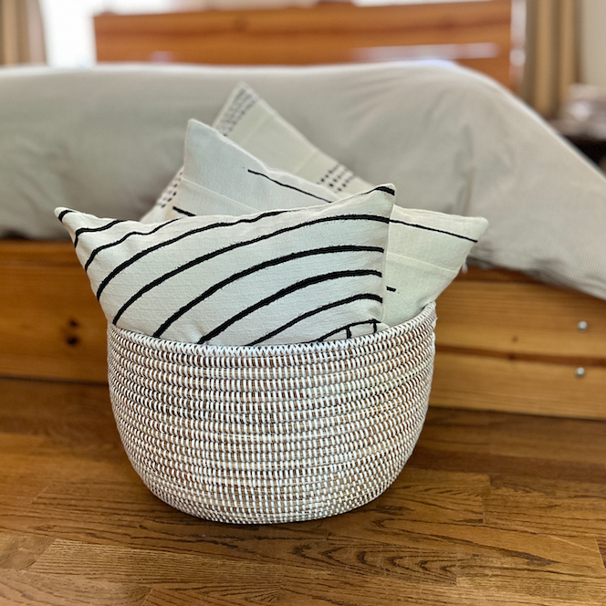 Woven oval basket holding folded light towels with black stripe patterns