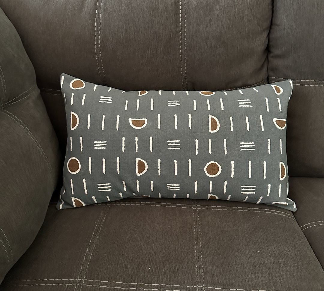 Lumbar pillow cover on dark sofa: dark gray with white mudcloth lines and brown ovals