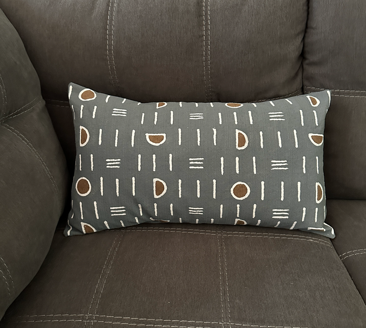 Lumbar pillow cover on dark sofa: dark gray with white mudcloth lines and brown ovals