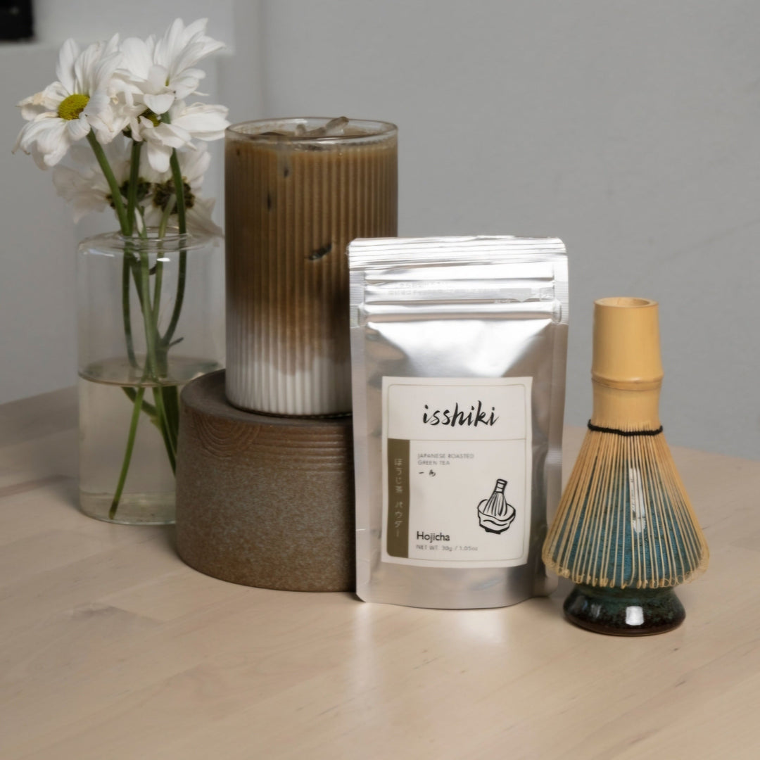 Hojicha roasted green tea powder pouch on tabletop with nearby whisk dispenser