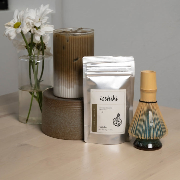 Hojicha roasted green tea powder pouch on tabletop with nearby whisk dispenser