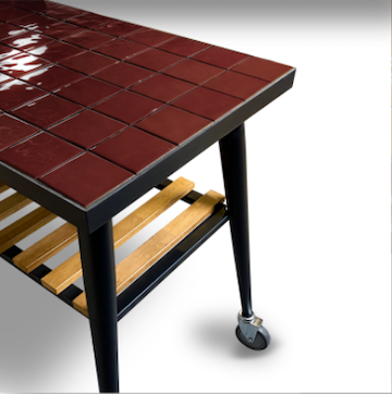 Outdoor grill cart with red tiled tabletop and lower storage grate on wheeled legs