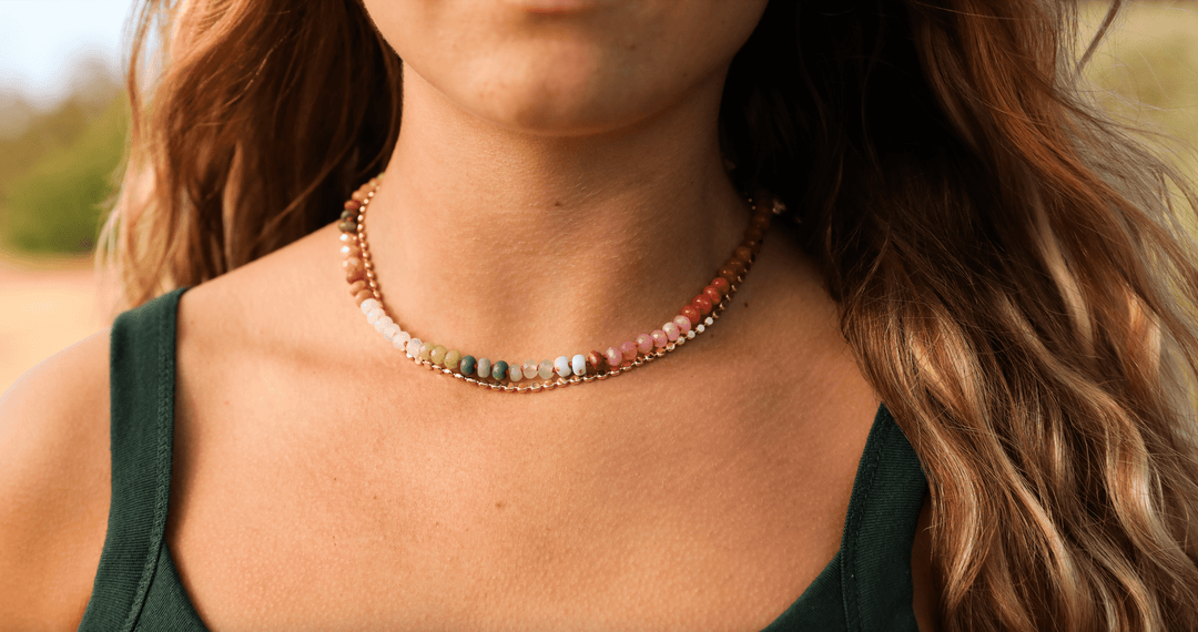 Multicolor gemstone beaded collar necklace with gold-tone beads, close-up on neckline