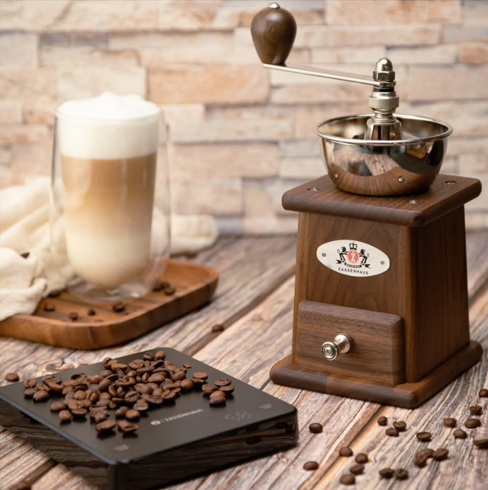 Walnut coffee grinder on wooden board with visible beans and metal grinding bowl