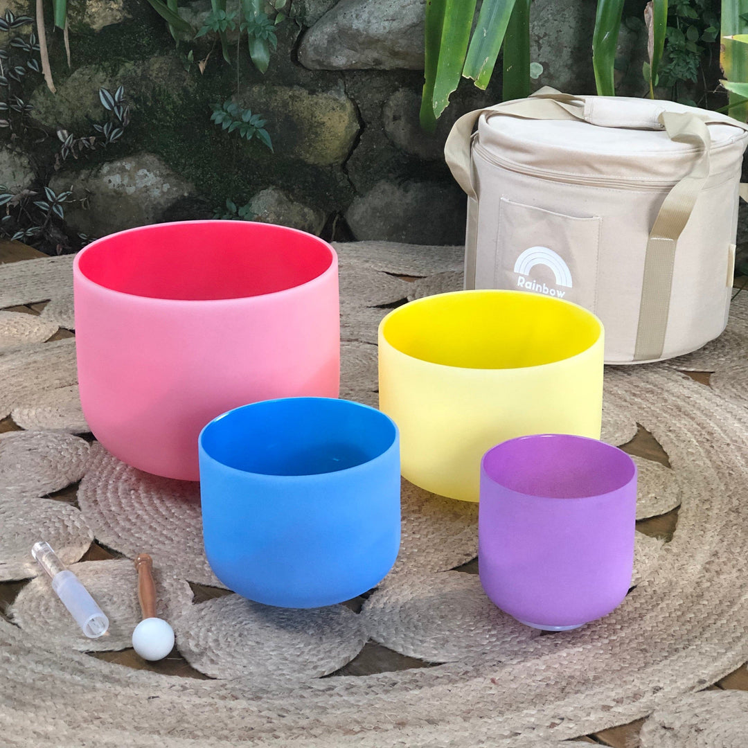 Set of 4 sound bowls in pink, yellow, blue, and purple with beige carry case